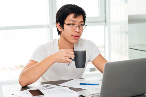 Software development student having coffee while working on a project