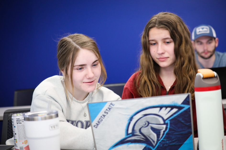 Two students working together on a project together using a computer
