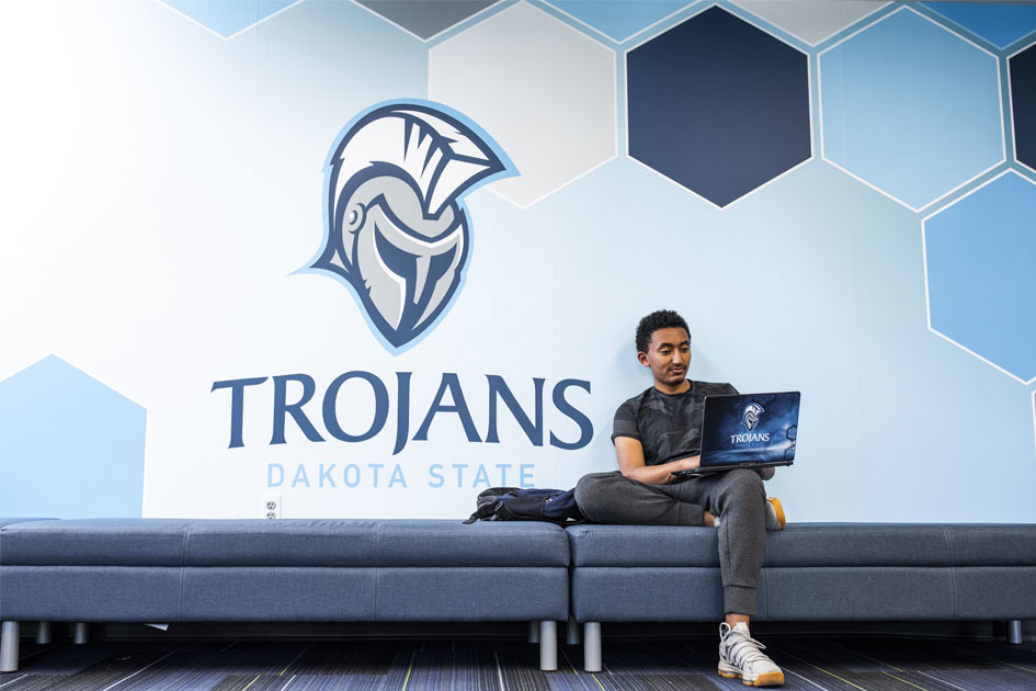 Student studying online in front of Trojan wall decal