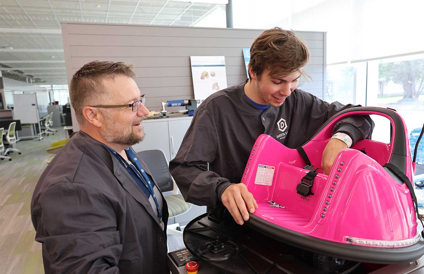 Dr. Justin Blessinger (left) and Nolan Rohl work on a zero-turn electric car.